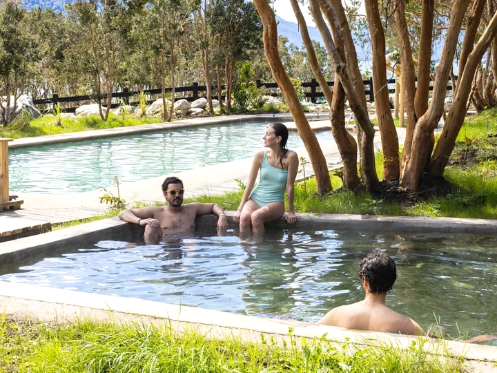 Personas en piscinas termales al aire libre rodeadas de árboles