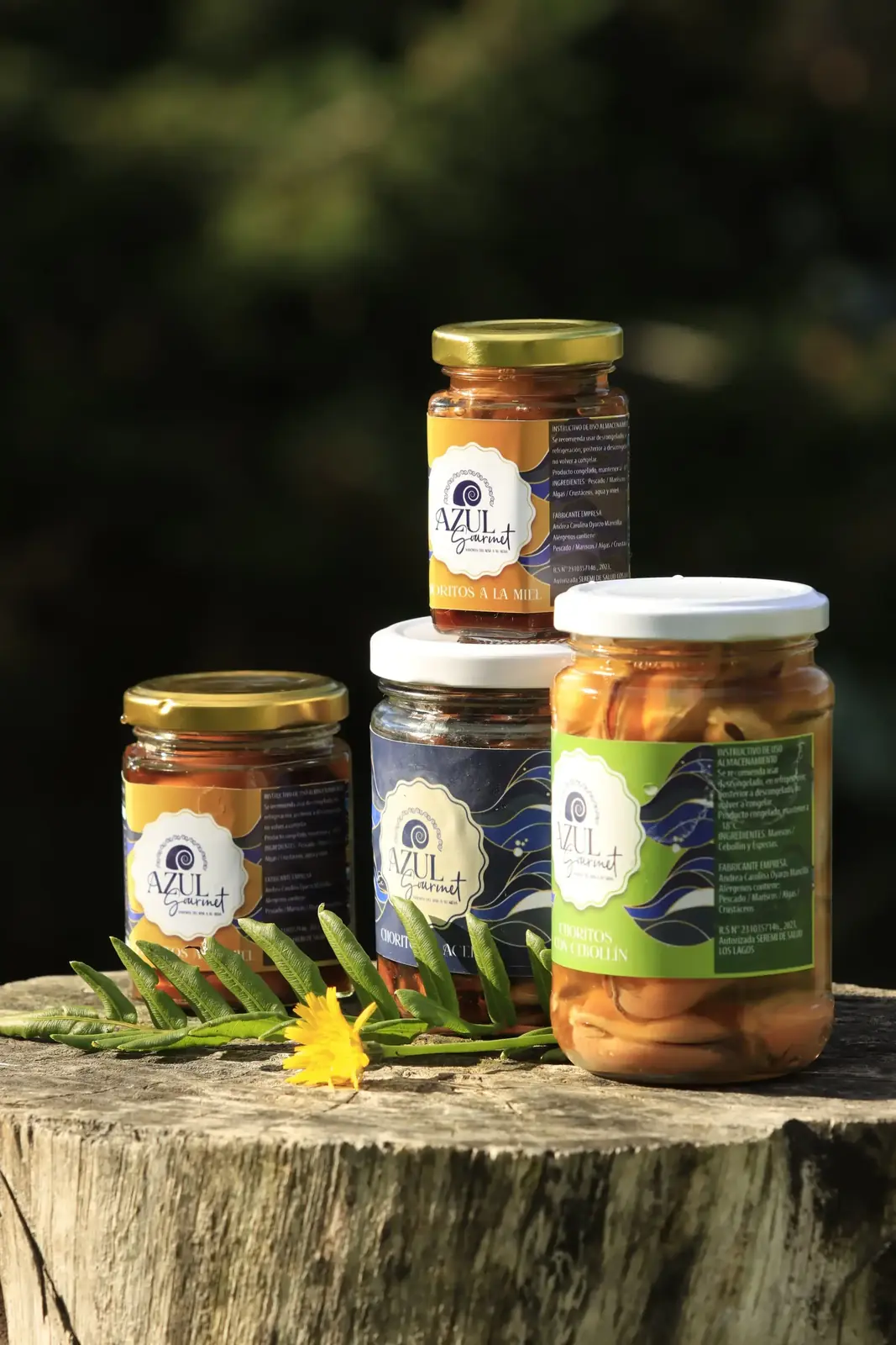 Frascos de conserva Azul Gourmet sobre un tronco, con el lago al fondo